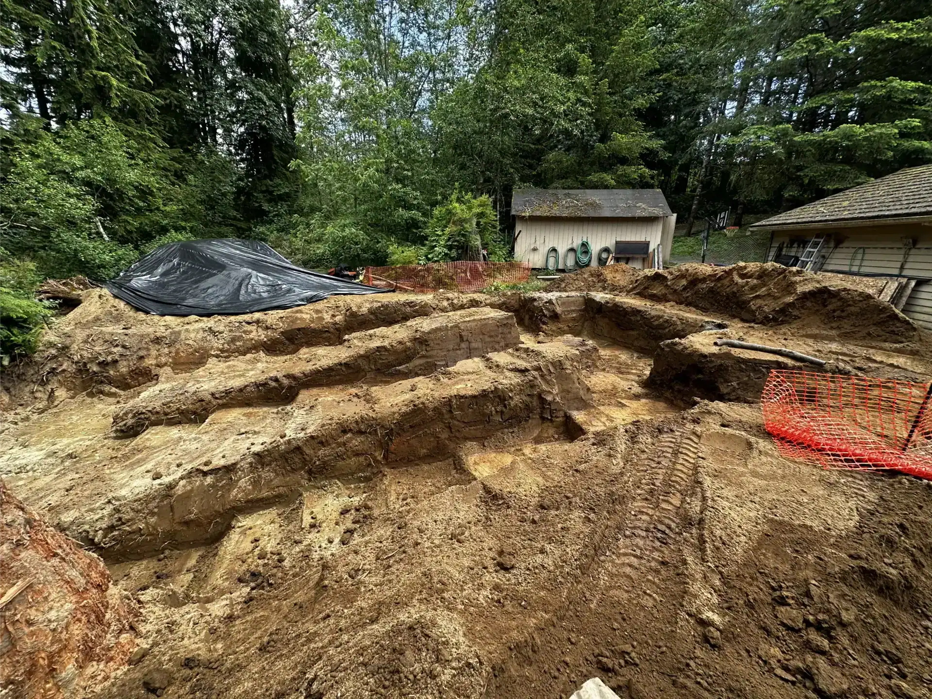 Excavation vs. Grading: What's the Difference? 1 Excavated construction site with stepped dirt levels, visible excavation tire tracks in the soil